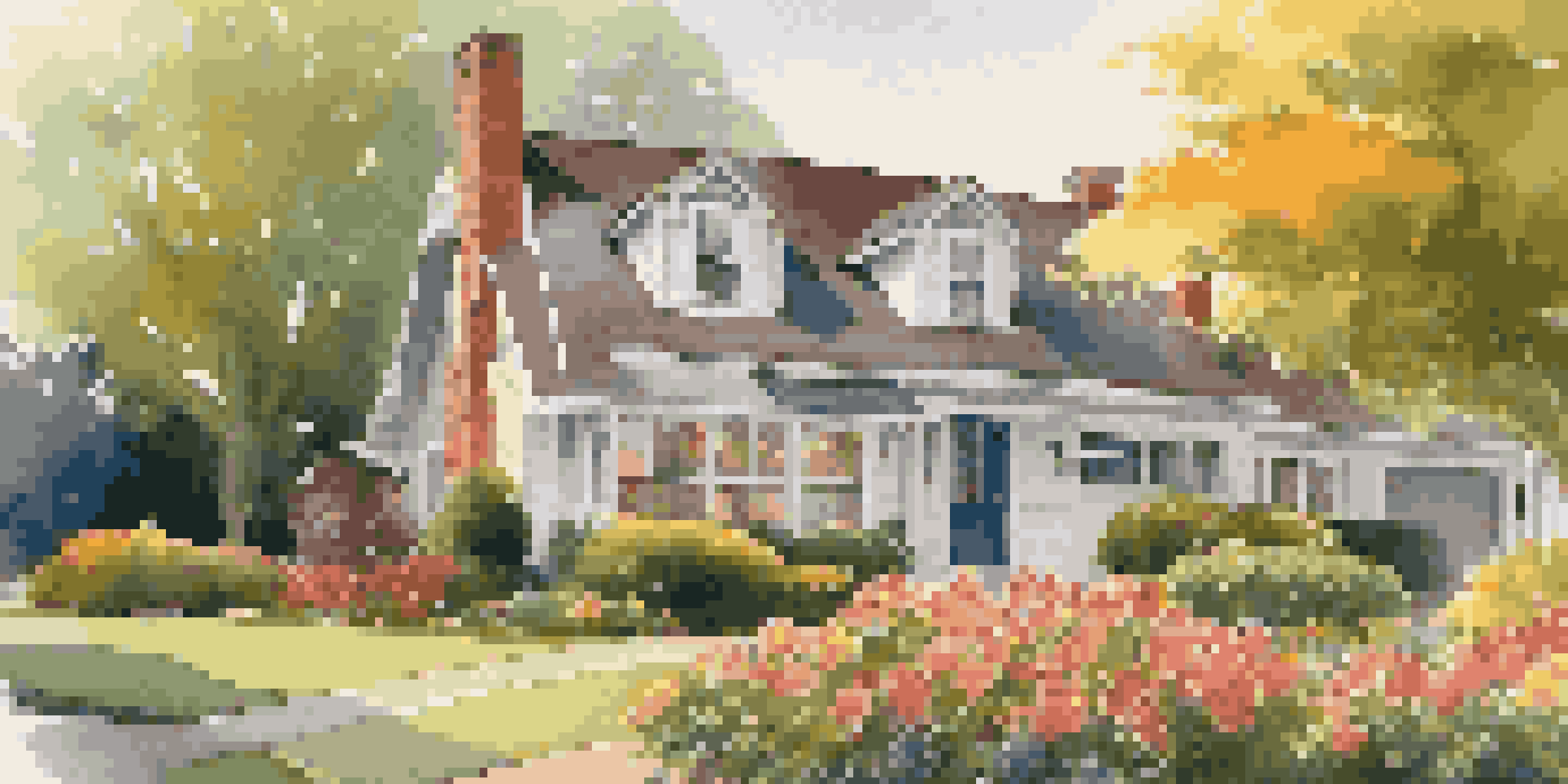 A close-up of a well-maintained suburban home with colorful flowers and a sunset background.