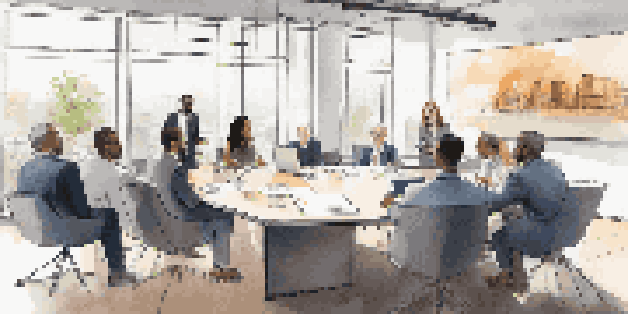 A diverse group of investors discussing a real estate project at a conference table, with laptops and financial graphs displayed on a screen.