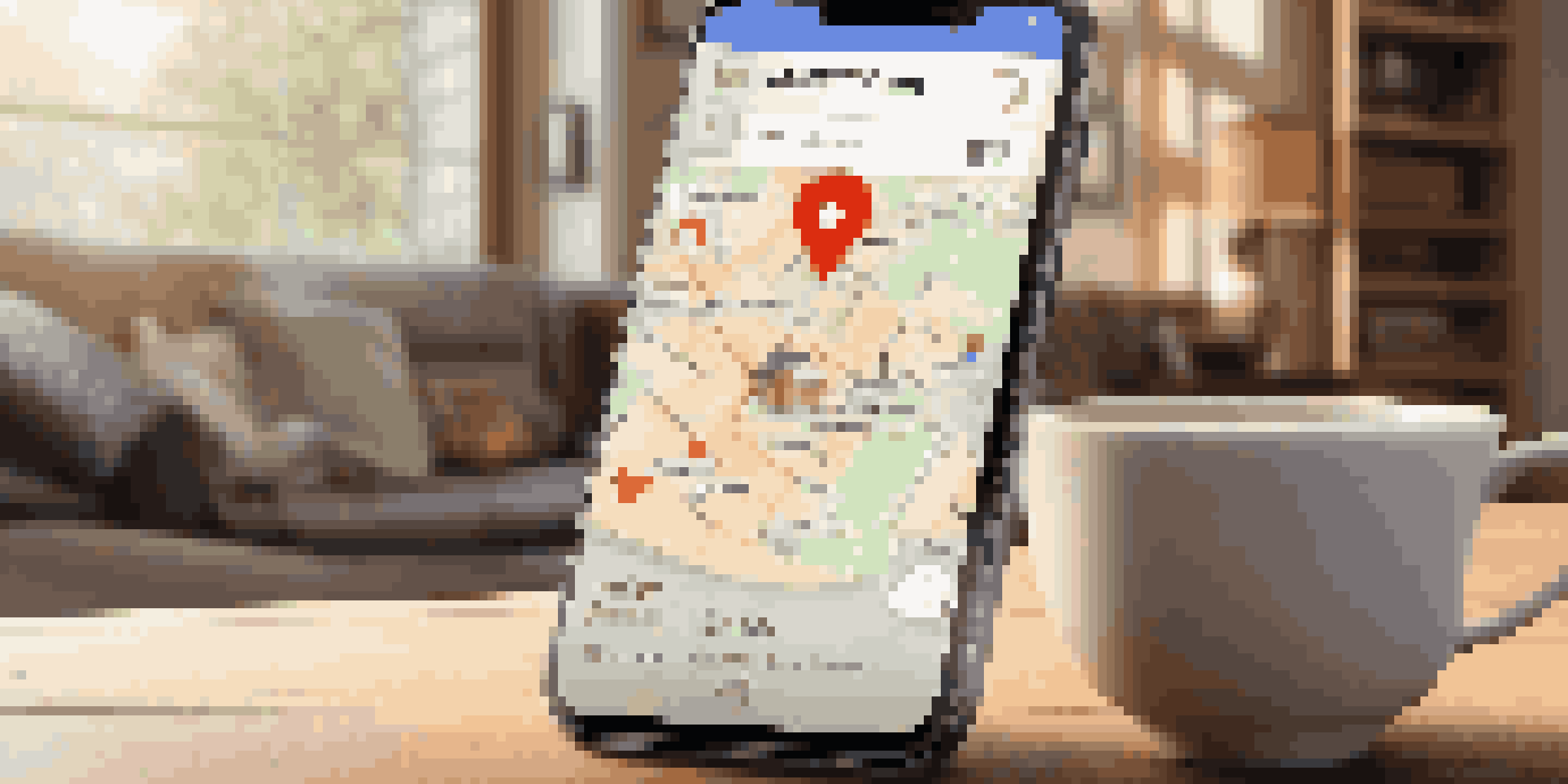 A smartphone showing a real estate app on a wooden table with a cup of coffee in a cozy living room.