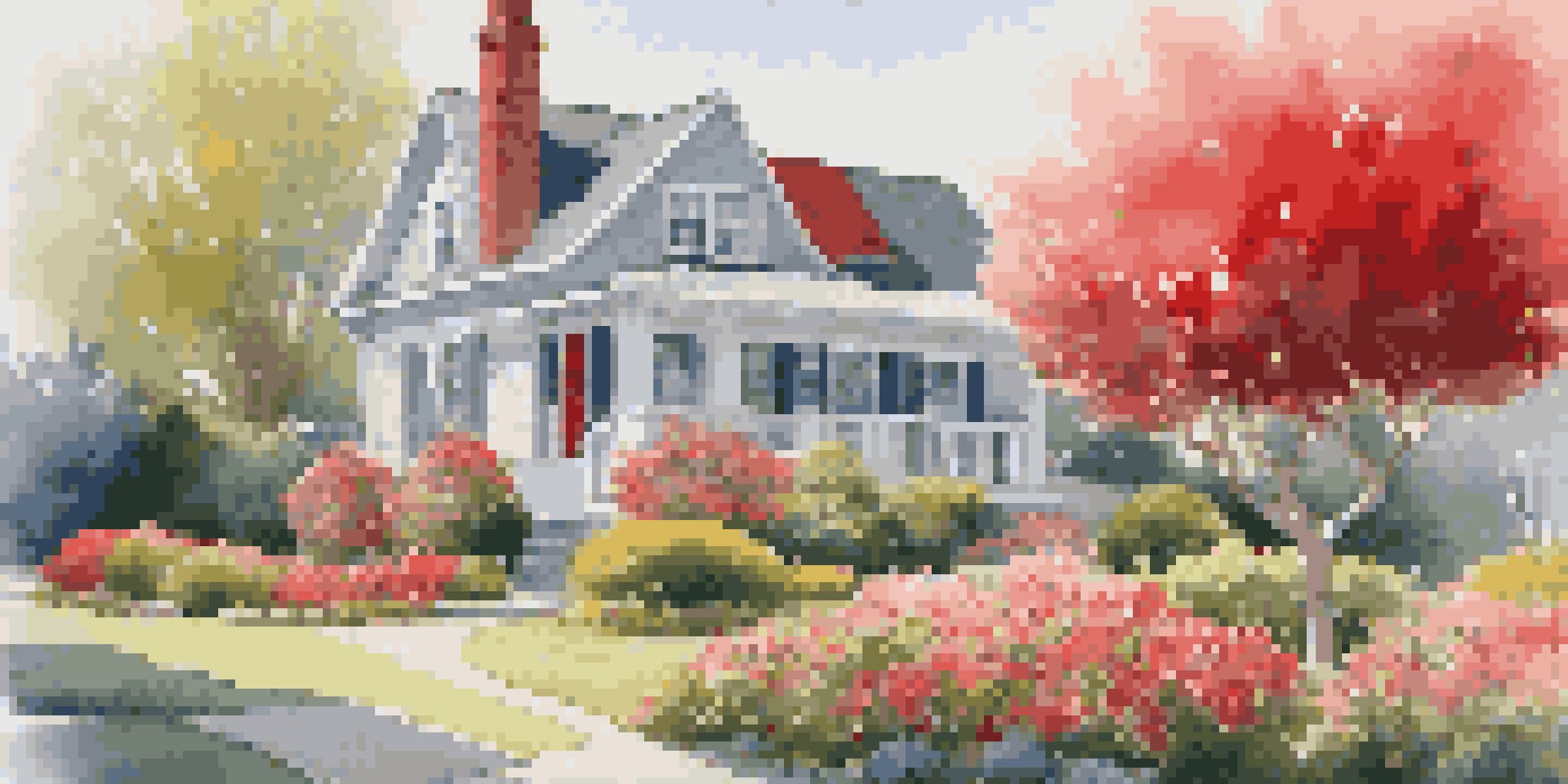 A beautiful front yard with colorful flowers and a red door on a gray house.