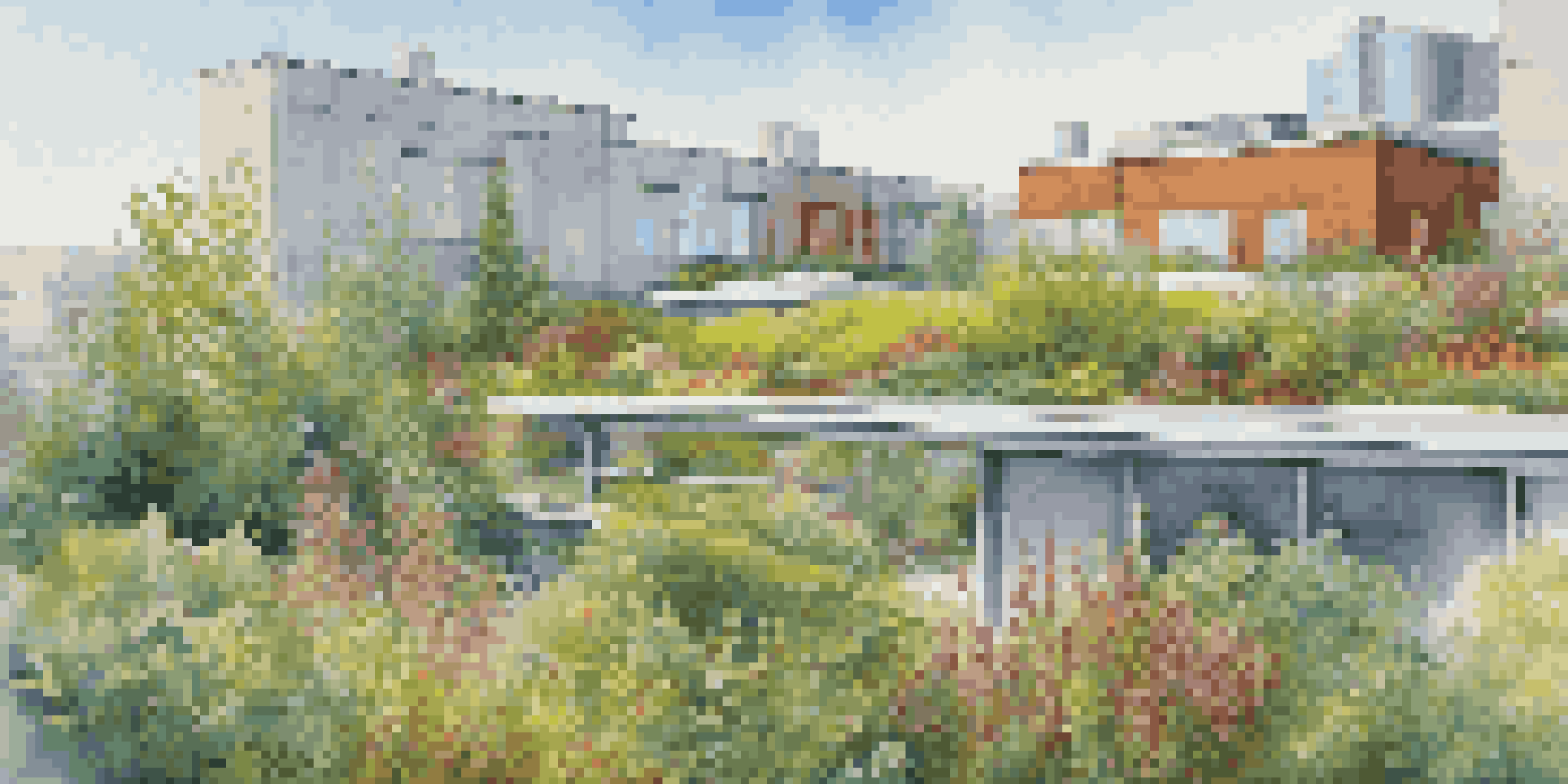 A colorful green roof with various plants and flowers on a modern building under a blue sky.