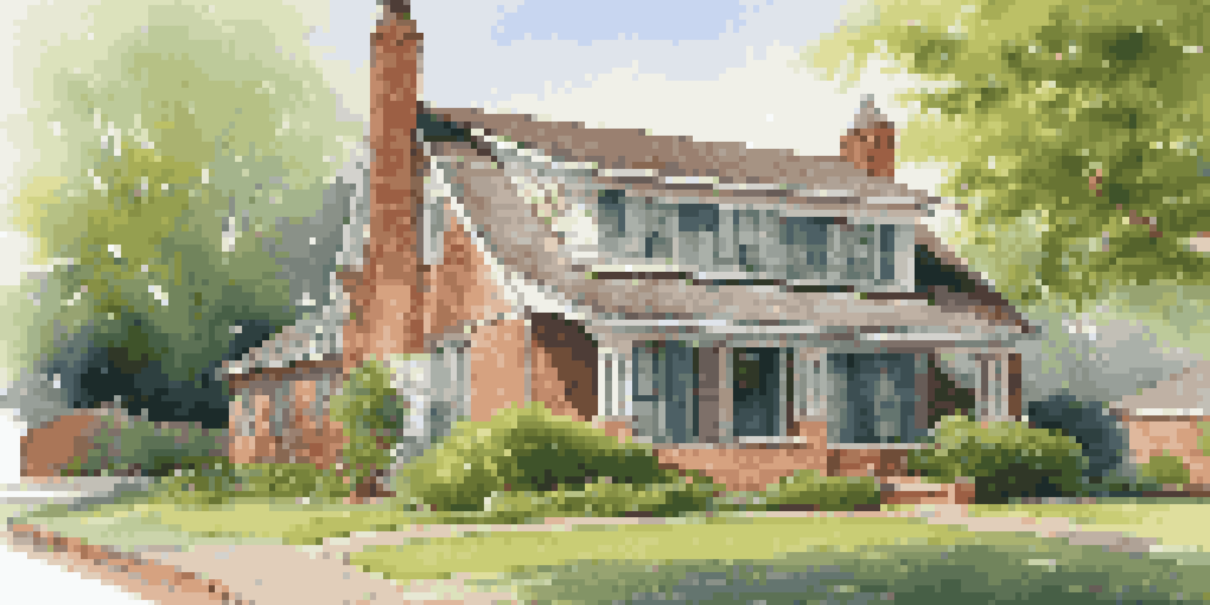 A picturesque old home with a clean roof and gutters, surrounded by vibrant green landscaping under a blue sky.