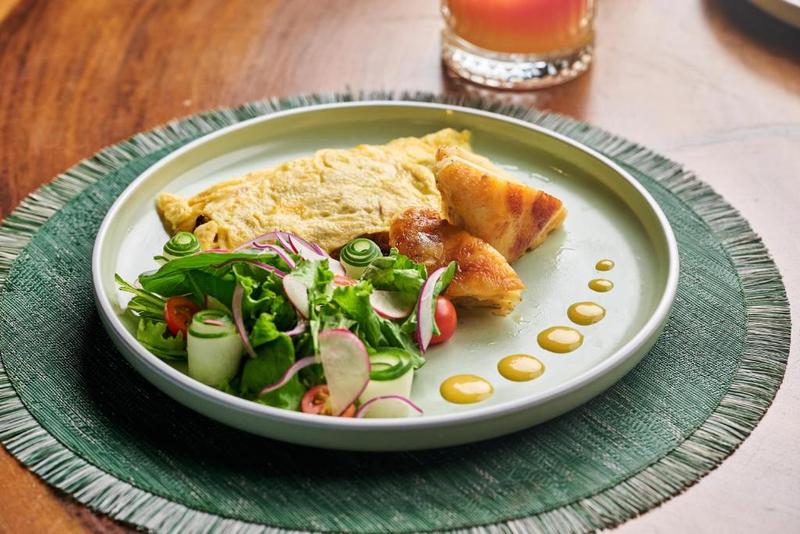 A plate of farm-to-table breakfast with omelette, fresh salad and fruit juice