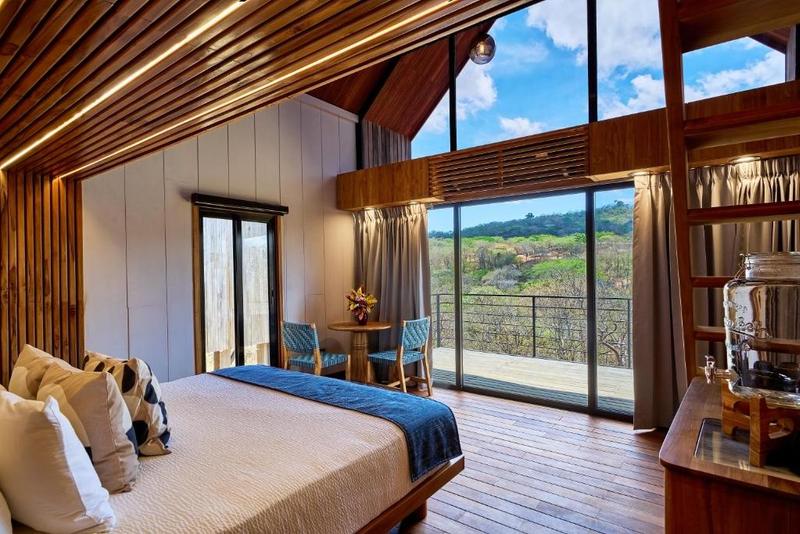 Treehouse suite interior with floor-to-ceiling windows opening to the jungle