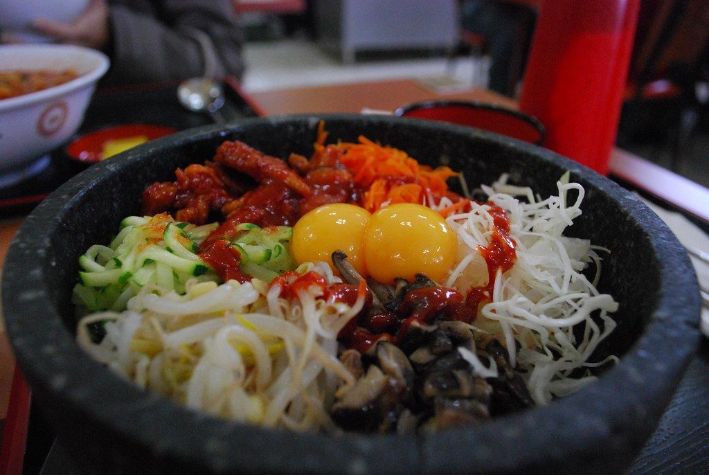 A dolsot (stone bowl) bibimbap with vegetables, egg yolks, and gochujang.