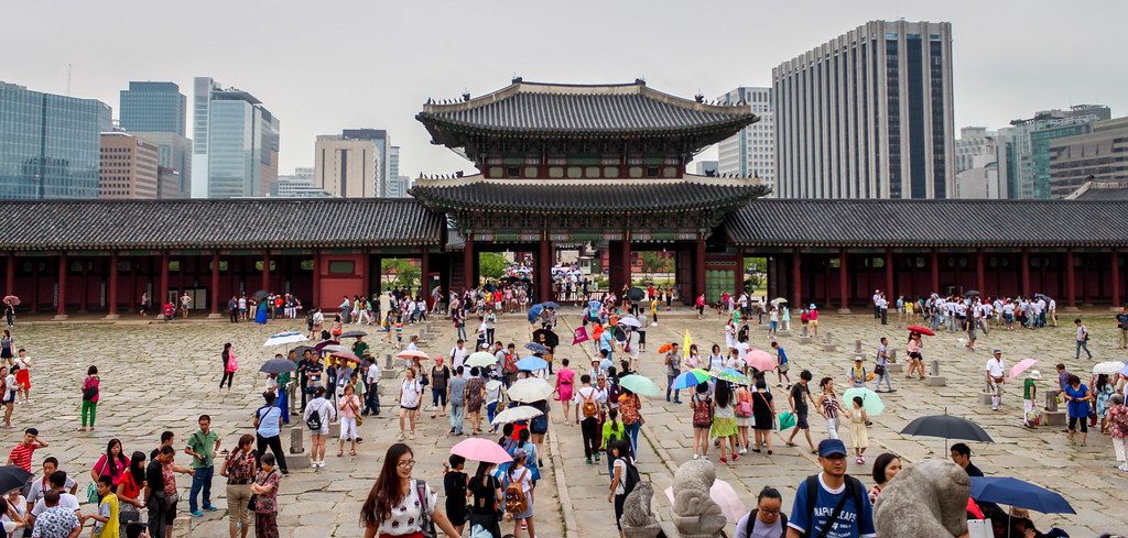 Gwanghwamun Gate and the Gyeongbokgung Palace courtyard in Seoul, with the city skyline behind.