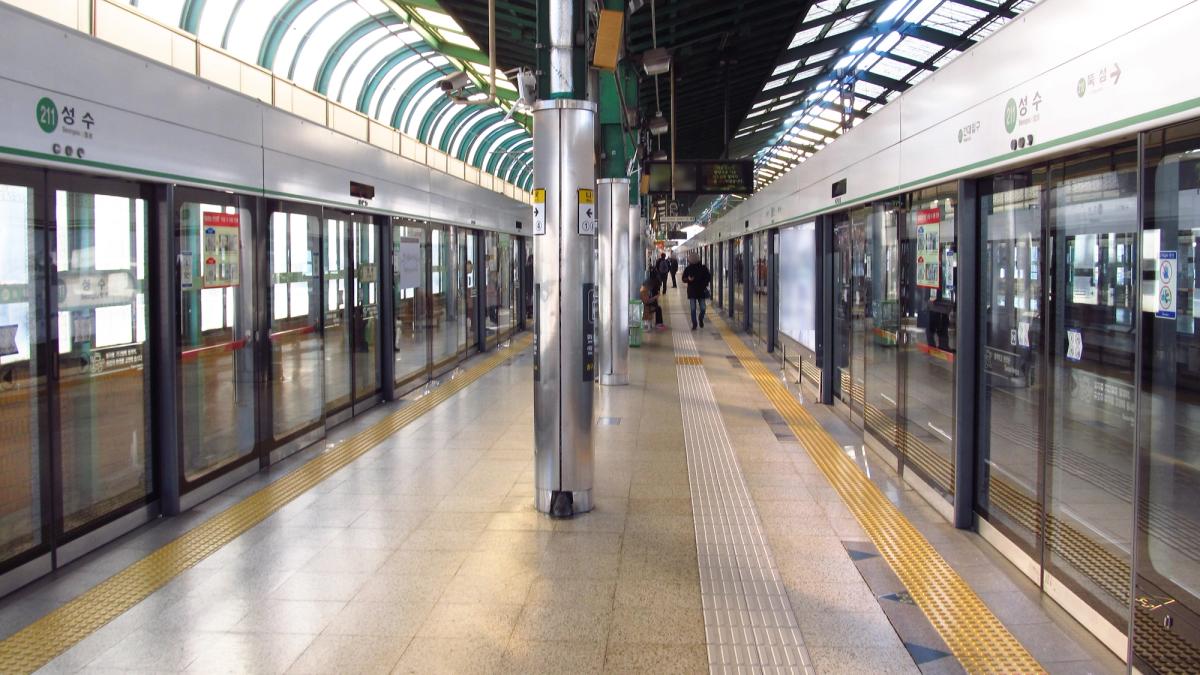 The platform at Seongsu Station on Seoul Metro Line 2, with 성수 (Seongsu) signs and the station's curved glass roof.