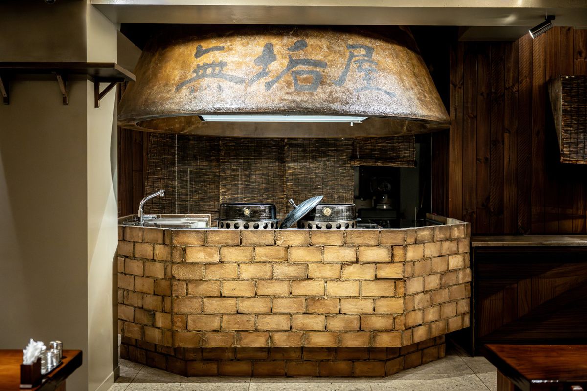 The brick cauldron station under the wooden 無垢屋 hood inside Muguok.