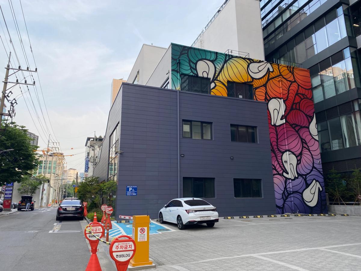 A Seongsu-dong backstreet in Seoul with a large, colorful mural covering the side of a building in the former factory district.
