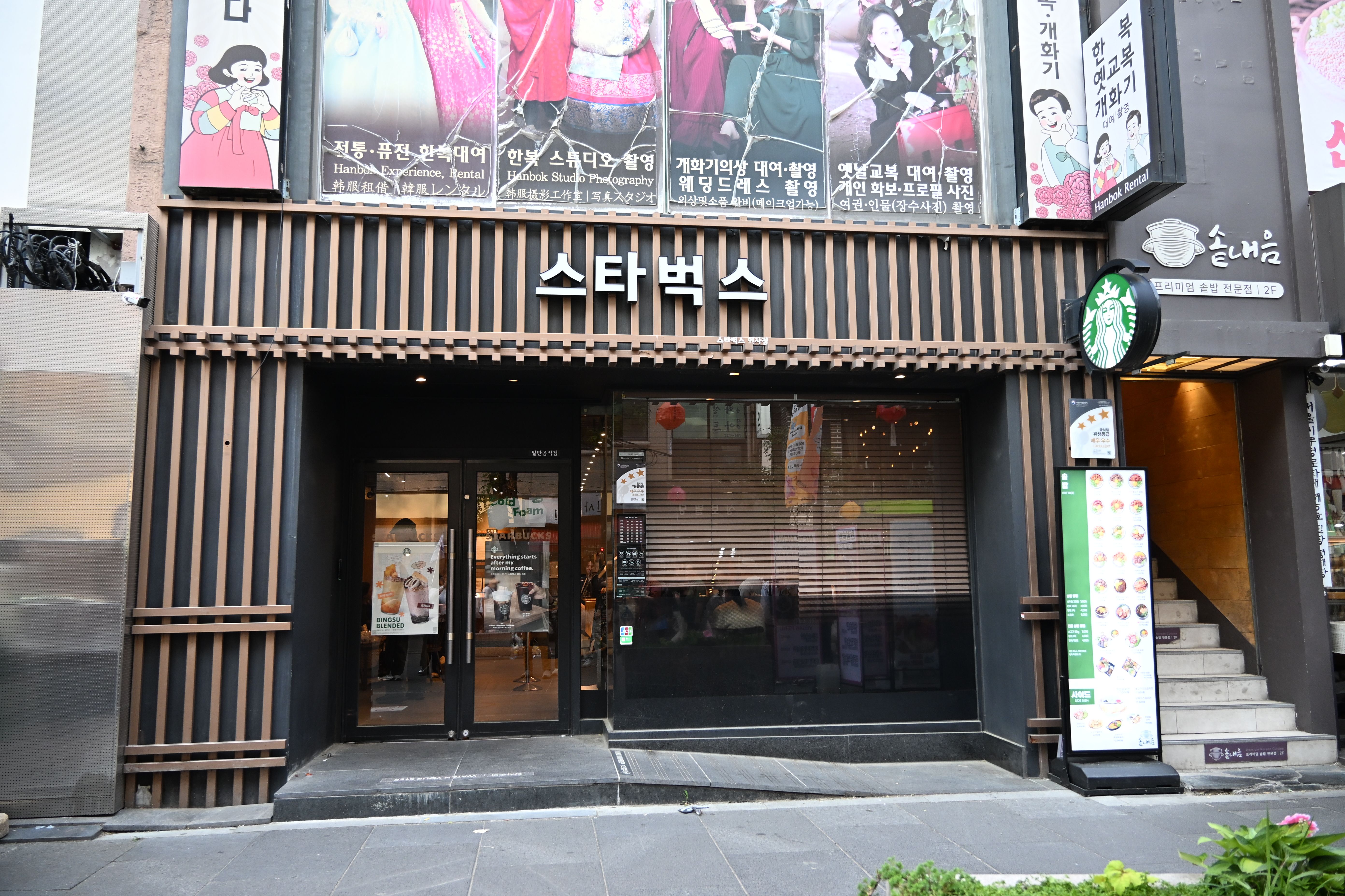 The Insadong Starbucks in Seoul, its storefront wrapped in a wooden-slat hanok facade with the sign written in Hangul as 스타벅스.