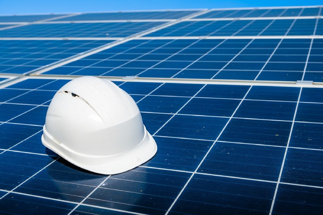 Solar cell contractor document with orange engineering team helmet on solar cells panels. Renewable energy and ecology concept — Credit: Photo by Evgeniy Alyoshin on Unsplash
