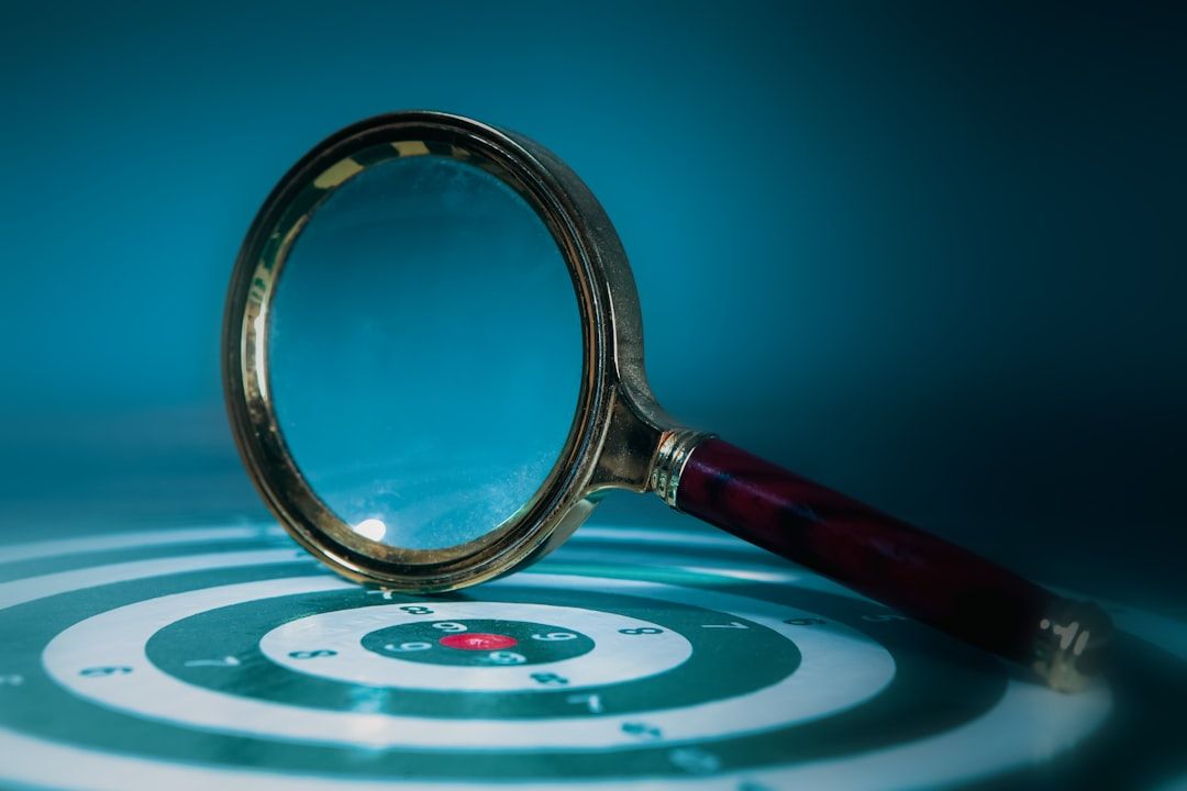 The image shows a magnifying glass resting on a target with concentric circles. The target features a red bullseye at its center, emphasizing focus and precision.