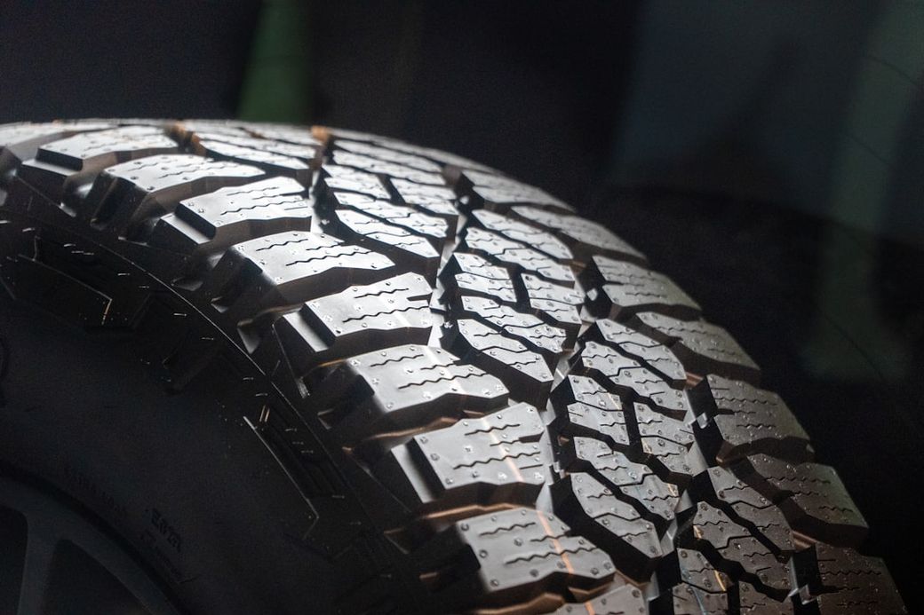 The image features a close-up view of a detailed tire tread, showcasing the intricate patterns designed for traction and grip. The background appears dark, emphasizing the texture and design of the tire. — Credit: Photo by Rob Wingate on Unsplash