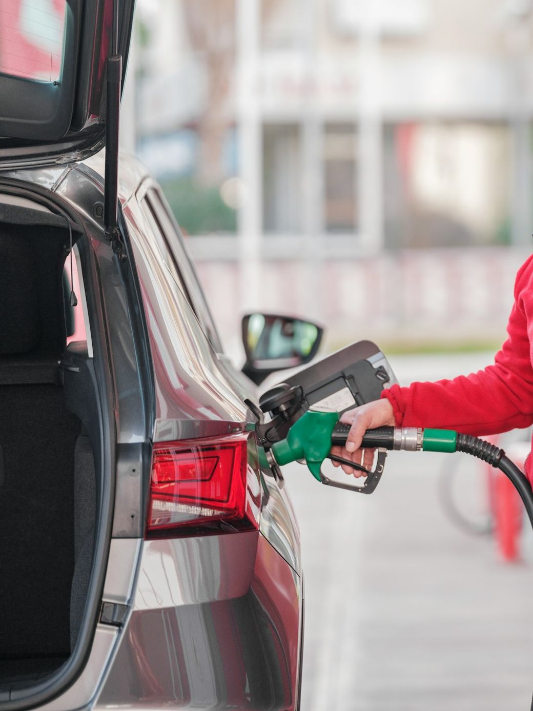 A person is seen refueling a vehicle at a gas station. The focus is on the act of fueling, highlighting the gas pump and the car's fuel tank. — Credit: Photo by engin akyurt on Unsplash