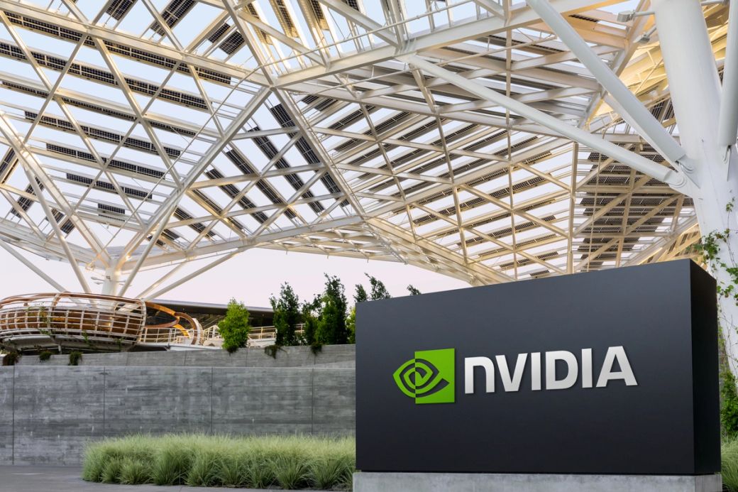 The image features the NVIDIA logo prominently displayed at the entrance of a modern building with an intricate architectural structure and greenery. The setting suggests a corporate environment, likely related to technology or innovation.