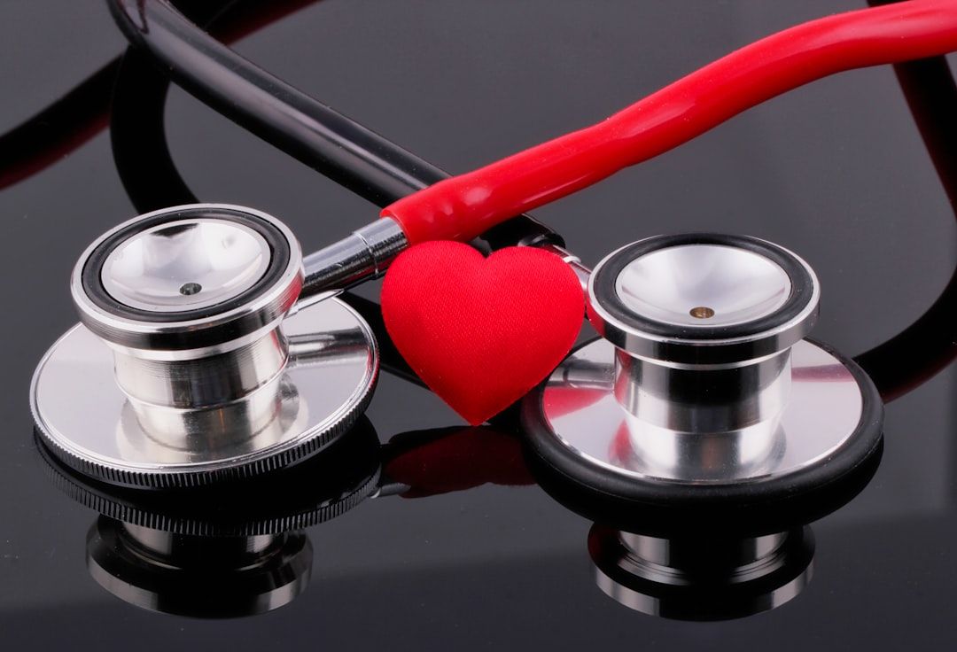 The image features two stethoscopes positioned beside a red heart, symbolizing healthcare and medical professions. The reflective surface adds a sleek, modern touch to the composition.
