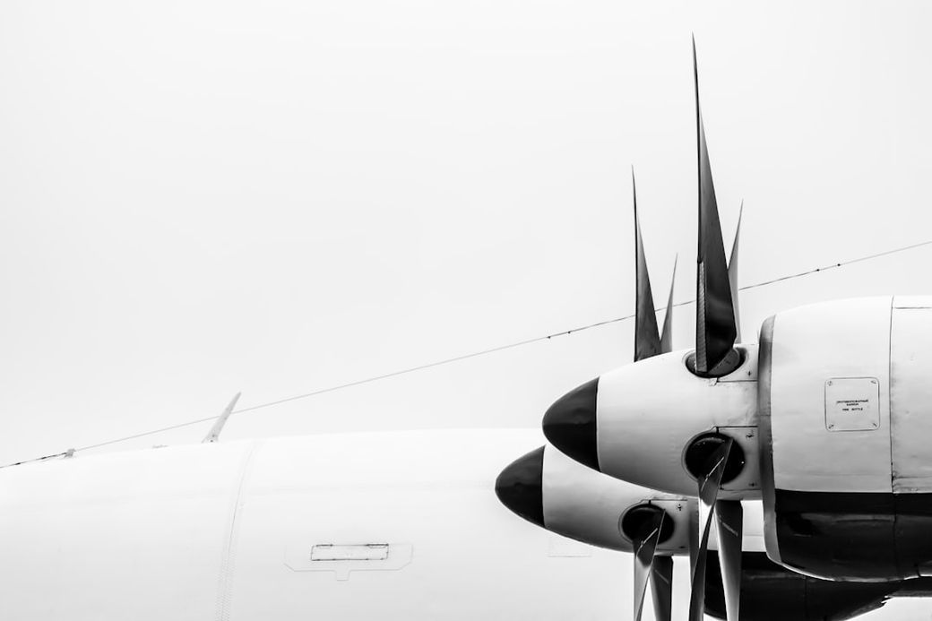The image showcases the propeller of an aircraft, emphasizing its aerodynamic design and mechanical details. The black and white contrast enhances the industrial aspect of aviation engineering. — Credit: Photo by K O on Unsplash