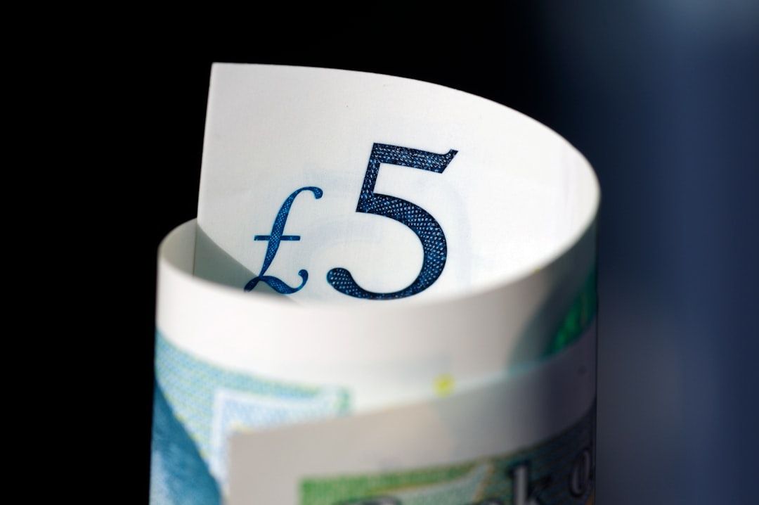 The image prominently features a folded £5 note, showcasing the denomination clearly. The background is dark, highlighting the details of the currency.
