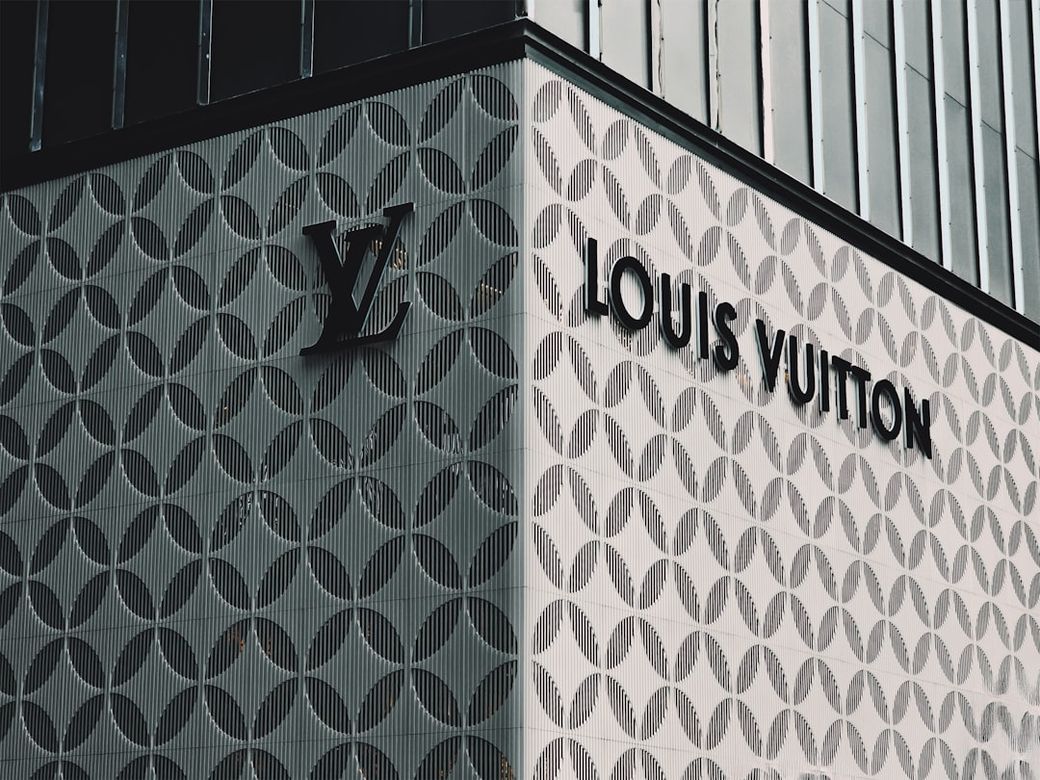 The image features the exterior of a luxury retail store displaying the iconic Louis Vuitton brand. The building showcases an elaborate facade design with the brand's logo prominently visible. — Credit: Photo by KC Shum on Unsplash
