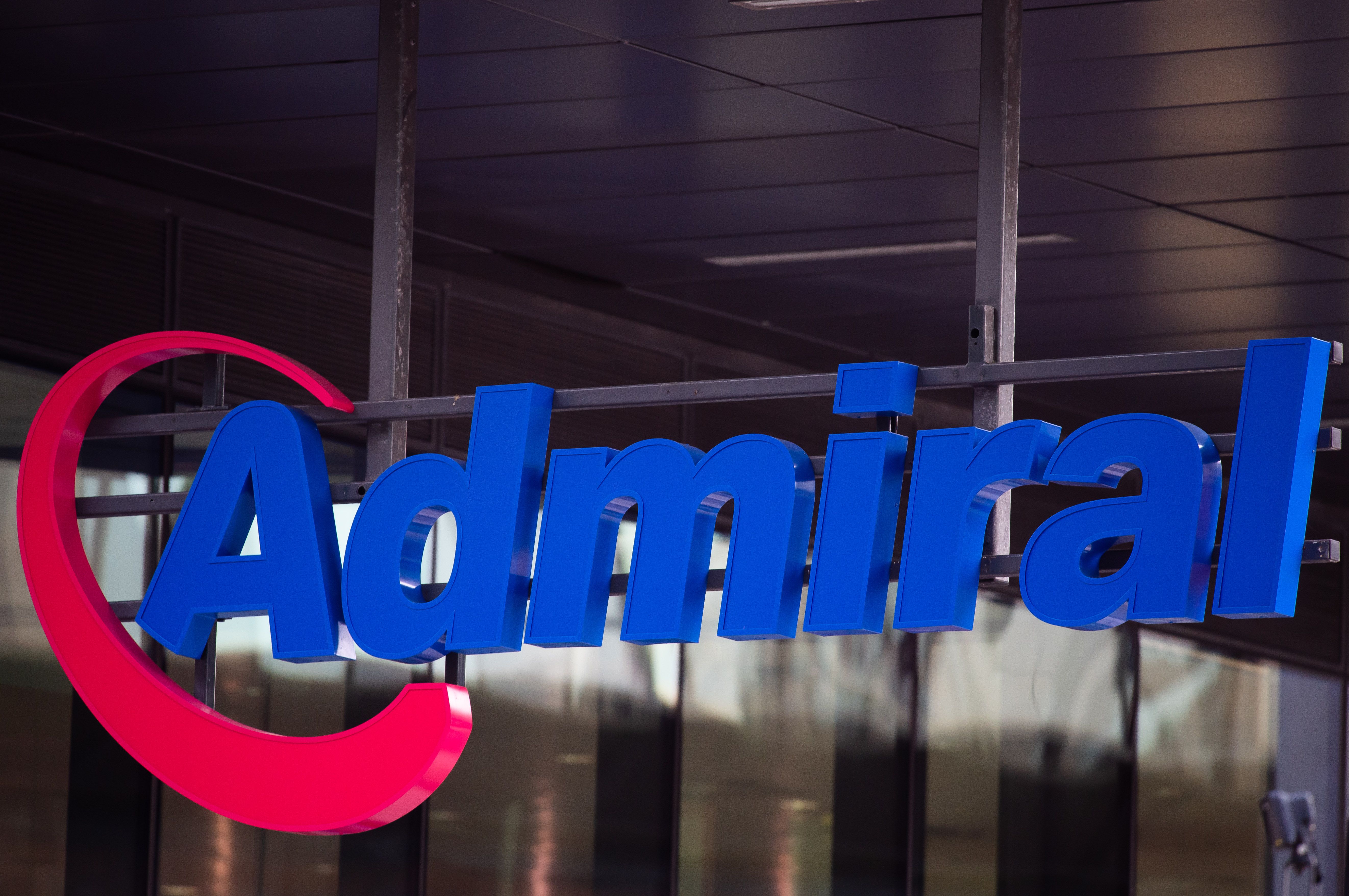 The image features a prominent sign for Admiral, a brand known for its insurance services. The sign is displayed in bright blue and red colors against a contemporary building backdrop.