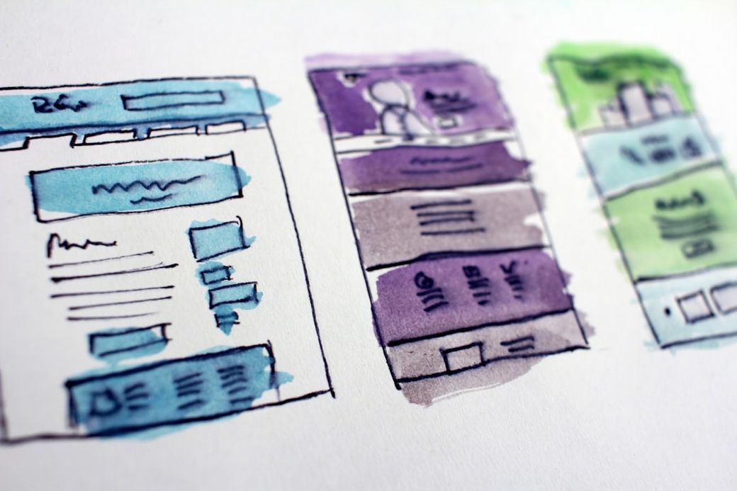 The image depicts a watercolor illustration of three web page layouts. Each layout features different color schemes and elements that suggest various website designs, possibly for different purposes. — Credit: Photo by Hal Gatewood on Unsplash