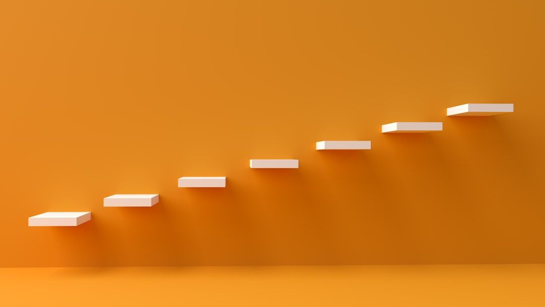 The image features a series of white, floating steps against a vibrant orange background. The steps ascend diagonally, creating a sense of progression or movement.