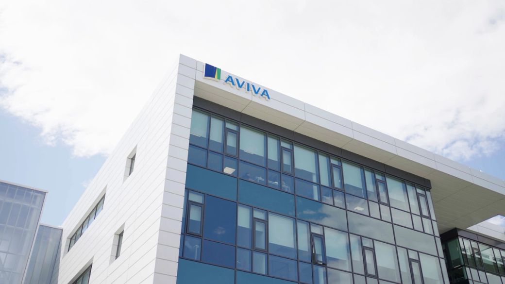 The image showcases a modern corporate building with a prominent logo of the company Aviva on the top. The building features a sleek design with large windows reflecting the sky.