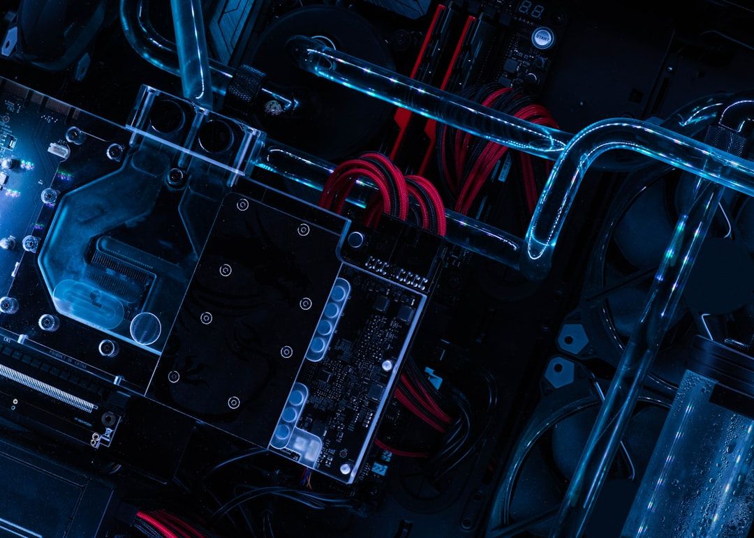 The image showcases an overhead view of a high-performance computer setup featuring intricate components like a graphics card and liquid cooling system. Vibrant blue lighting enhances the technological aesthetic of the hardware.
