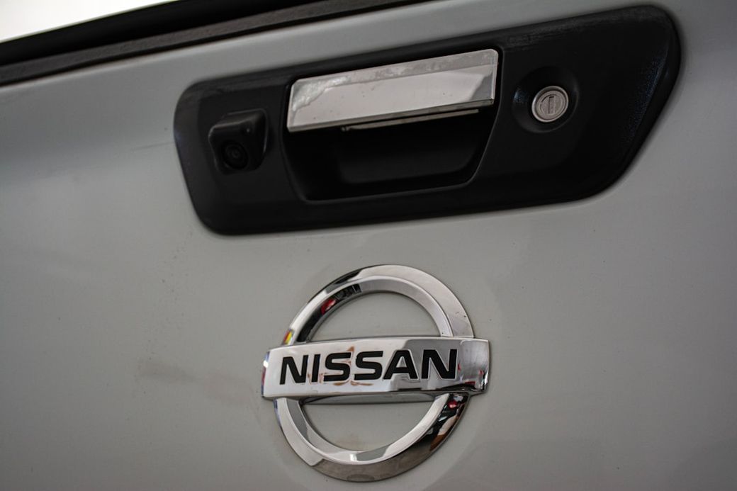 The image features the rear of a vehicle with a clear view of the Nissan logo and a door handle. The setting is likely a garage or workshop environment, emphasizing automotive design. — Credit: Photo by igor constantino on Unsplash