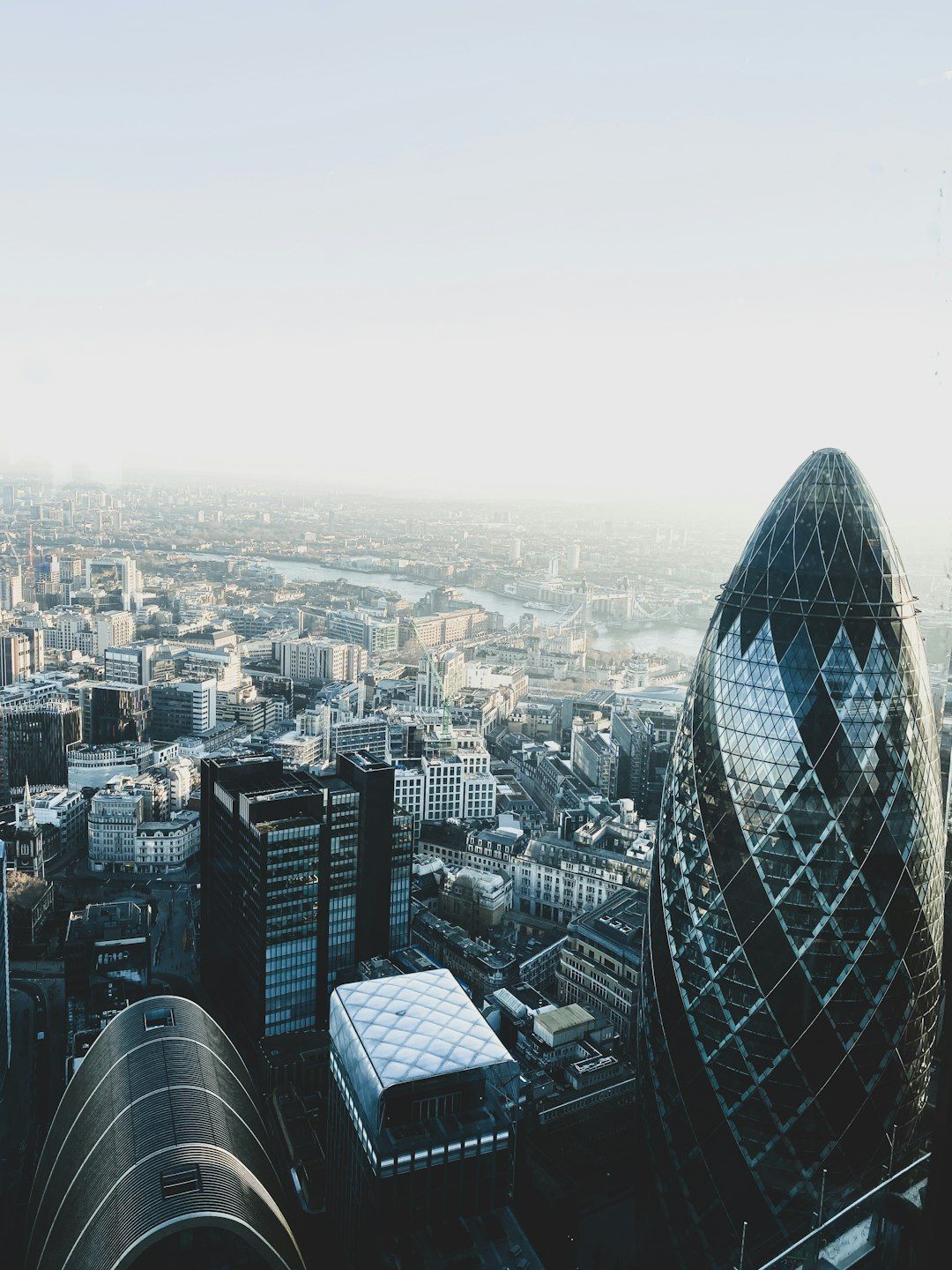 The image shows a panoramic view of a city skyline featuring modern architecture, including the distinctive rounded structure known as 'The Gherkin'. The scene captures a clear sky and a sprawling urban landscape.