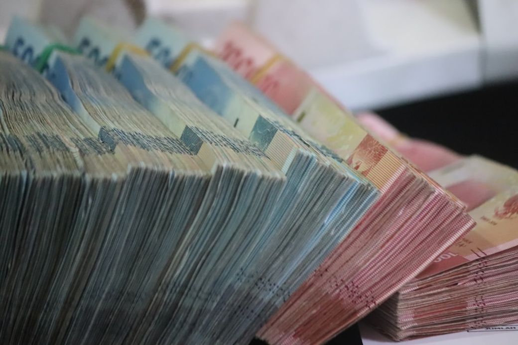 The image showcases a close-up view of neatly stacked bundles of banknotes in various denominations. The colorful currency is arranged in an organized manner, highlighting the different values distinctively. — Credit: Photo by Mufid Majnun on Unsplash
