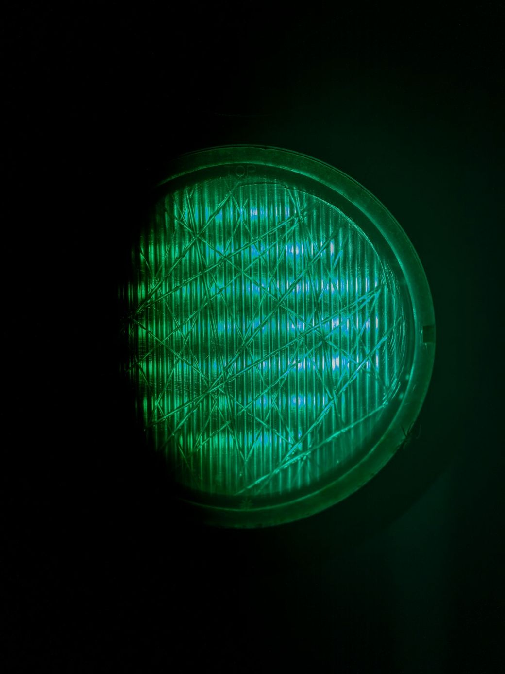 The image features a close-up view of a green light source, possibly indicating a signal or status. The texture and pattern of the light's surface are visible against a dark background, emphasizing the glowing effect. — Credit: Photo by Haberdoedas on Unsplash