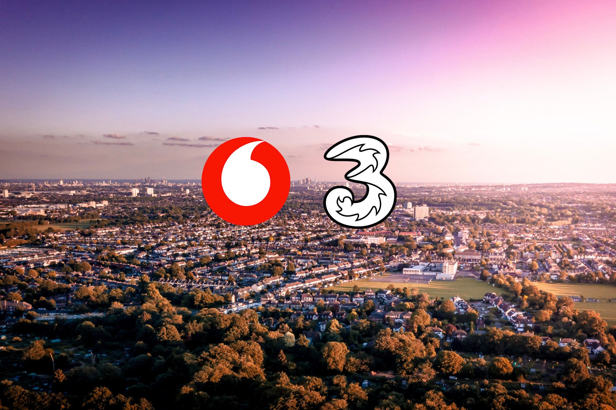 An aerial view of a cityscape featuring urban development and greenery. Prominently displayed are the logos of Vodafone and a stylized number 3.