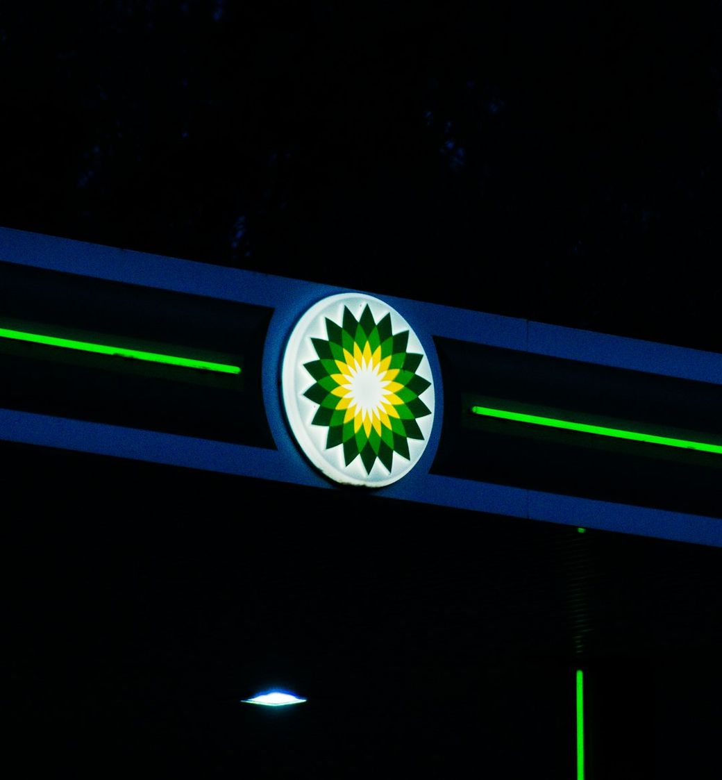 The image features a brightly lit BP gasoline station sign against a dark background. The iconic green and yellow logo is clearly visible, indicating the fuel station's brand. — Credit: Photo by Simon Cheung on Unsplash