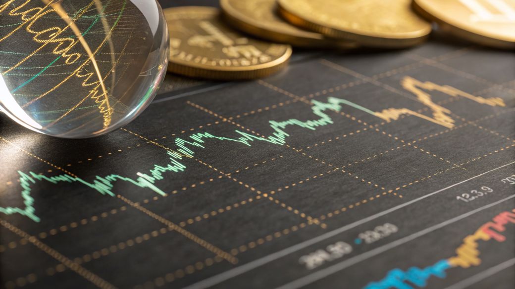 The image features a close-up view of a stock market chart with fluctuating data lines in green and blue. In the background, there are stacks of coins, suggesting a focus on financial investment or trading.