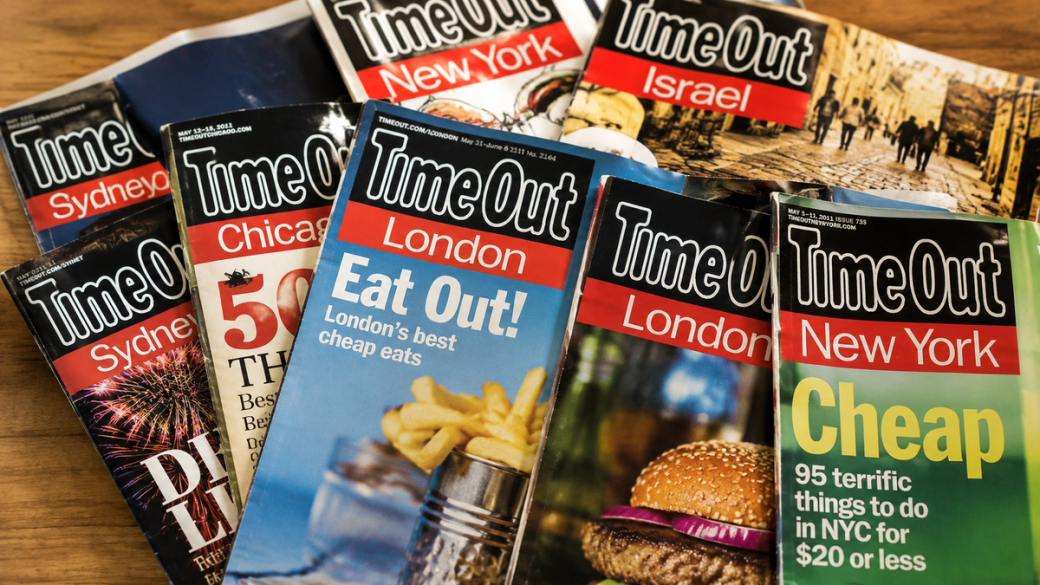 The image showcases a collection of 'Time Out' magazine issues featuring different cities, including New York, London, Sydney, and Chicago. Each cover highlights local attractions and dining options, emphasizing the magazine's role in providing travel and culinary recommendations.