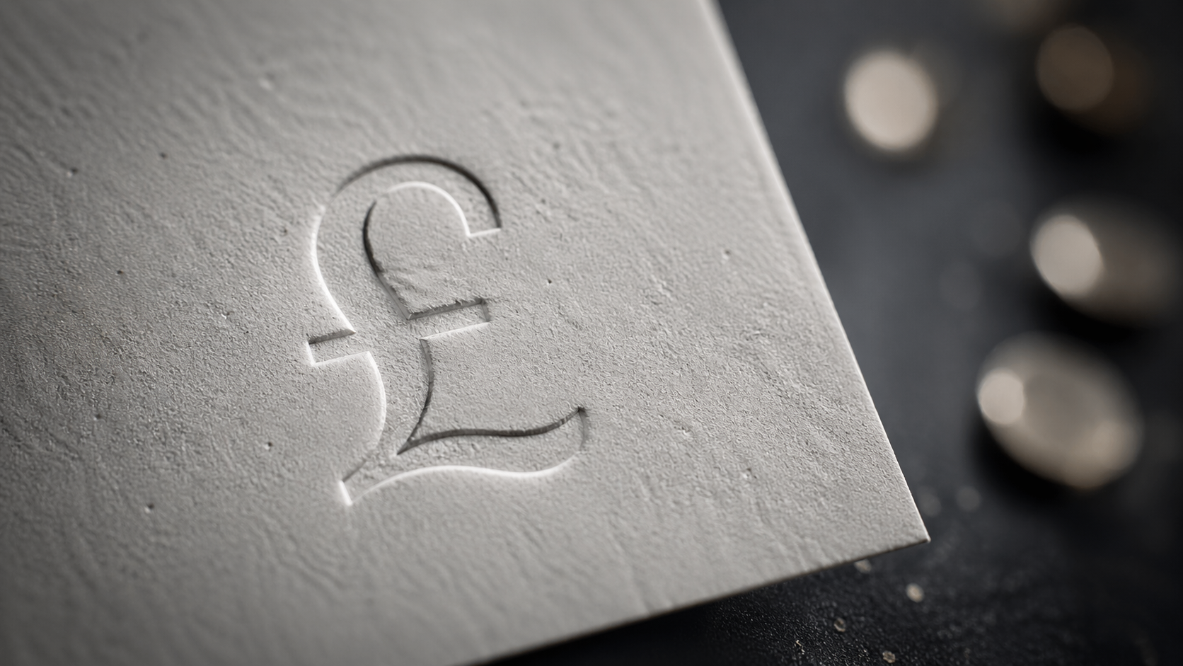 The image showcases a close-up view of a textured surface featuring an embossed pound currency symbol. Surrounding the symbol are scattered coins, suggesting a focus on British currency.