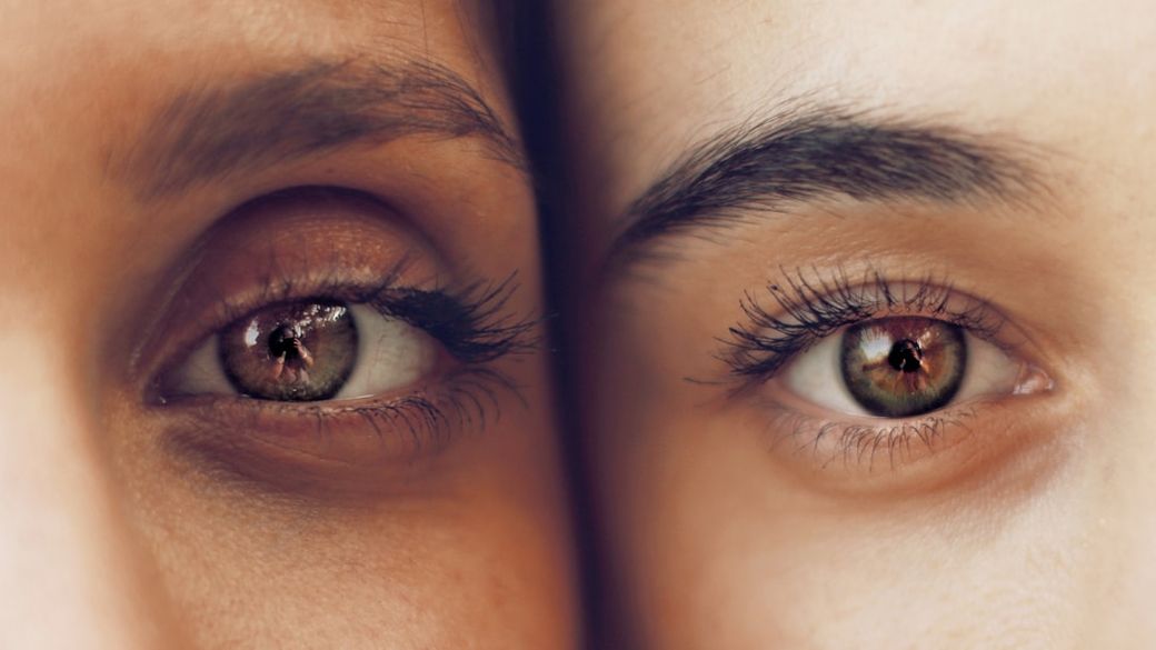The image features a close-up of two faces positioned side by side, focusing on their eyes. Both eyes have distinct features, showcasing different tones and reflections. — Credit: Photo by Soroush Karimi on Unsplash
