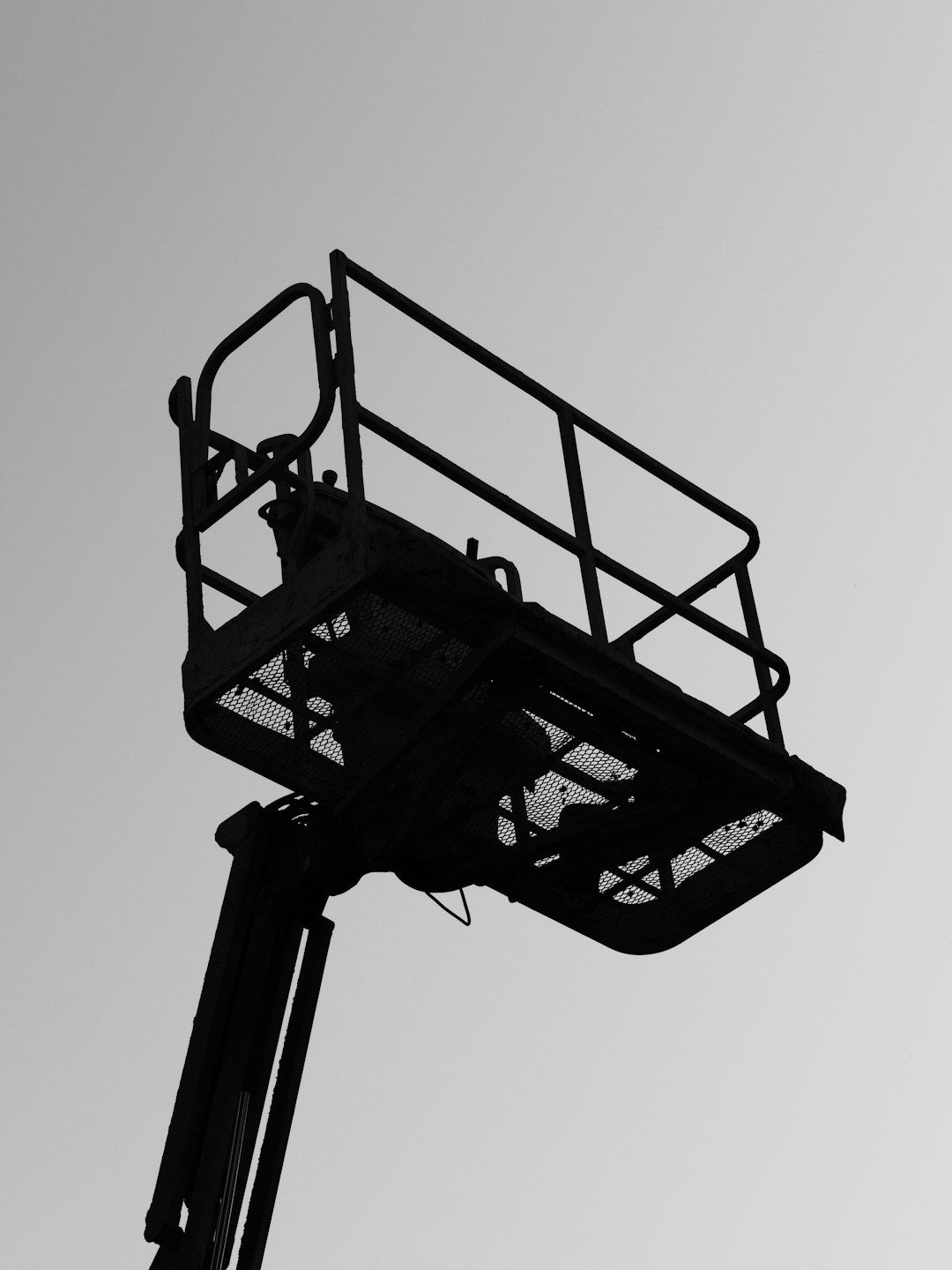 The image features the silhouette of a construction lift or cherry picker against a clear sky. The structure includes a platform with railings, commonly used for accessing high places during construction or maintenance work.