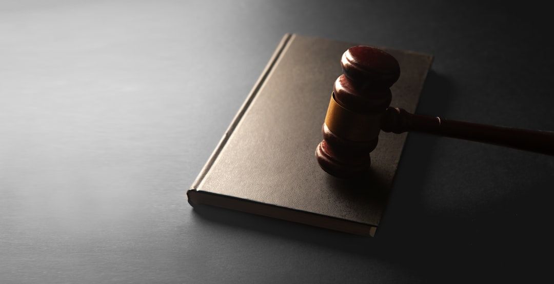 The image features a wooden gavel resting on a closed legal book, symbolizing justice and law. The neutral background accentuates the gavel and book, creating a professional atmosphere.
