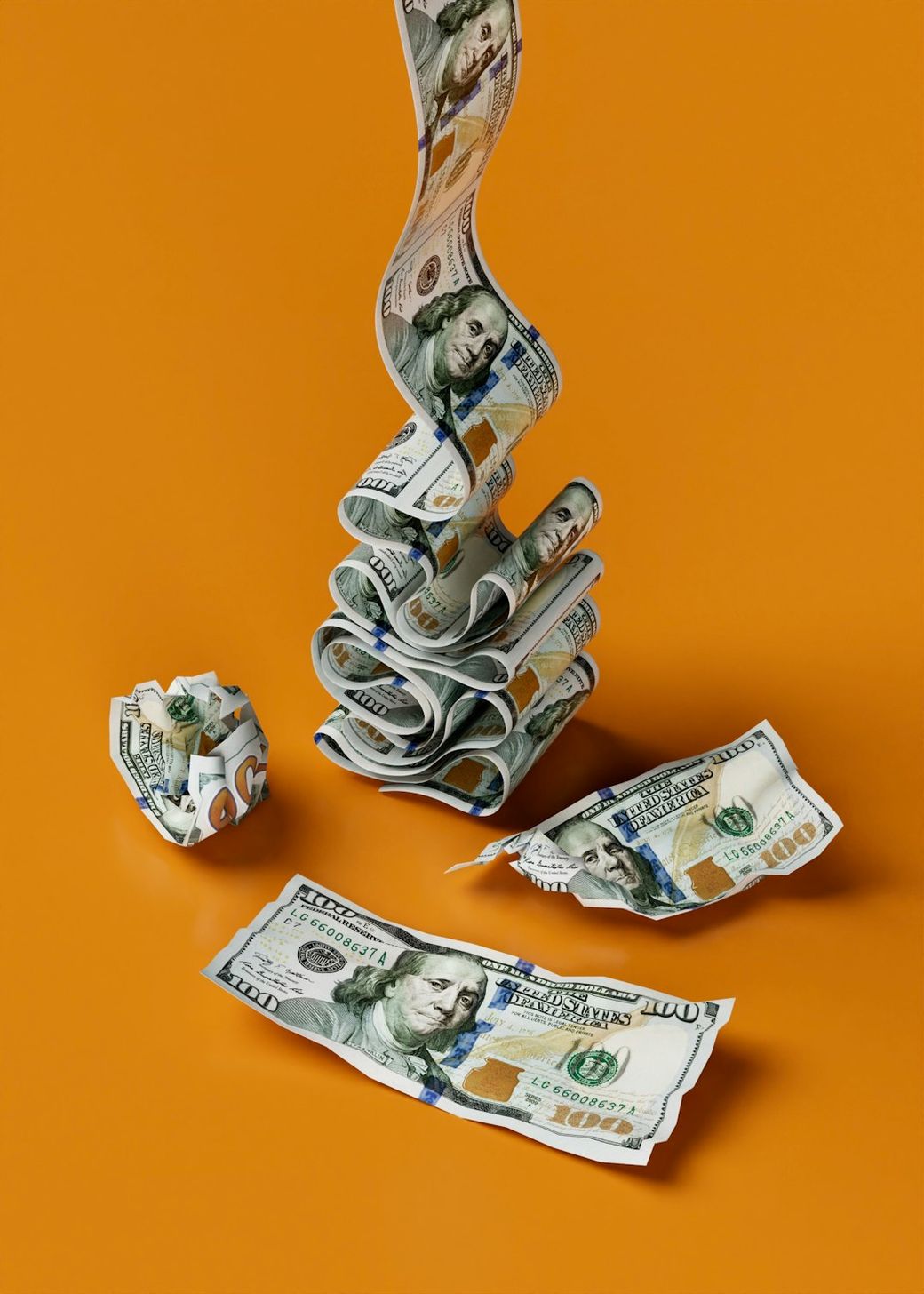 The image features a creative arrangement of U.S. dollar bills, with some bills stacked and others rolled or crumpled, set against an orange background. The artistic presentation suggests themes of finance and wealth. — Credit: Photo by Igor Omilaev on Unsplash