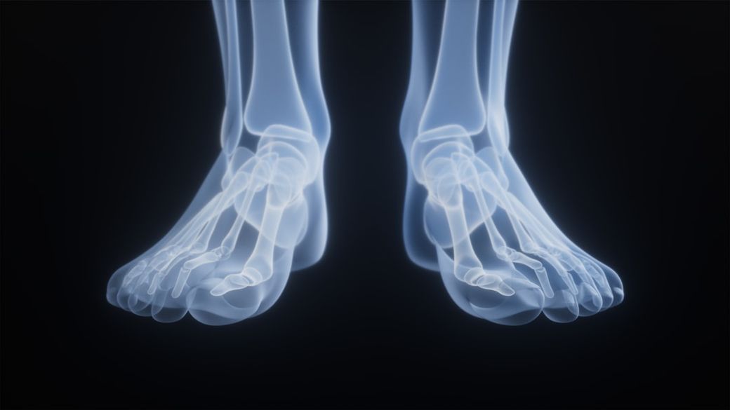 The image features a close-up of an X-ray representation of two human feet, highlighting the skeletal structure. The translucent bones are displayed against a dark background, emphasizing the intricate details of the foot anatomy. — Credit: Photo by Rohit Choudhari on Unsplash