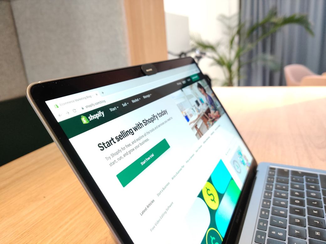 The image features a laptop displaying the Shopify website. The screen showcases a call to action for starting a selling platform, suggesting an e-commerce context. — Credit: Photo by hookle.app on Unsplash