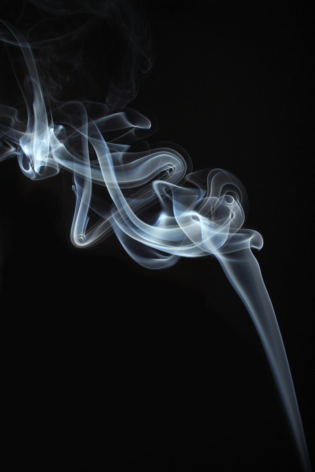 The image illustrates swirling smoke patterns against a dark background, showcasing the ethereal and fluid nature of smoke. The soft curves and wisps create a dynamic visual effect, emphasizing motion and delicacy. — Credit: Photo by Thomas Stephan on Unsplash