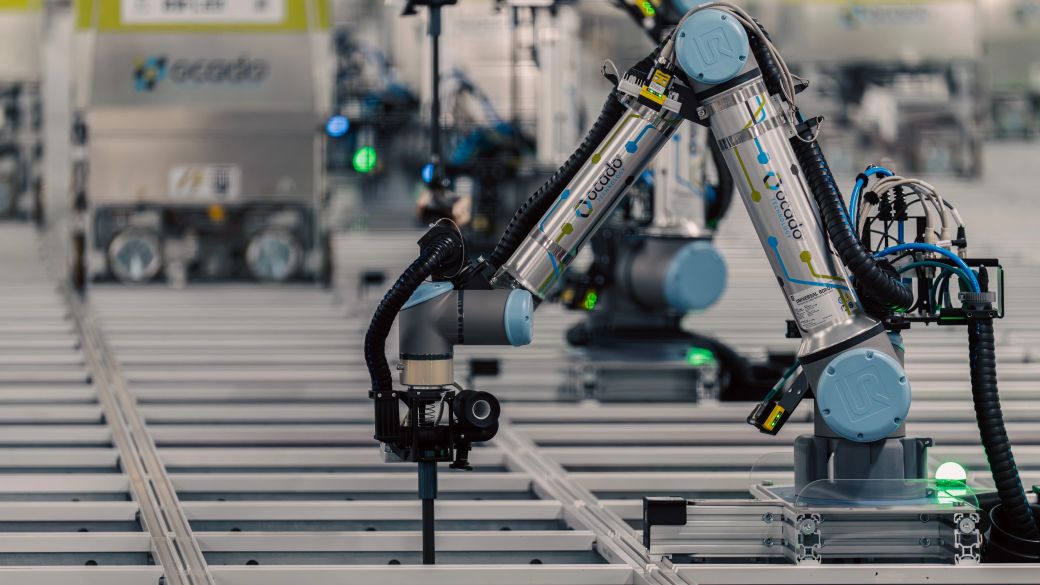 The image showcases advanced robotic systems in a high-tech warehouse environment. These robots are equipped with various tools and are engaged in automated tasks related to logistics and inventory management.