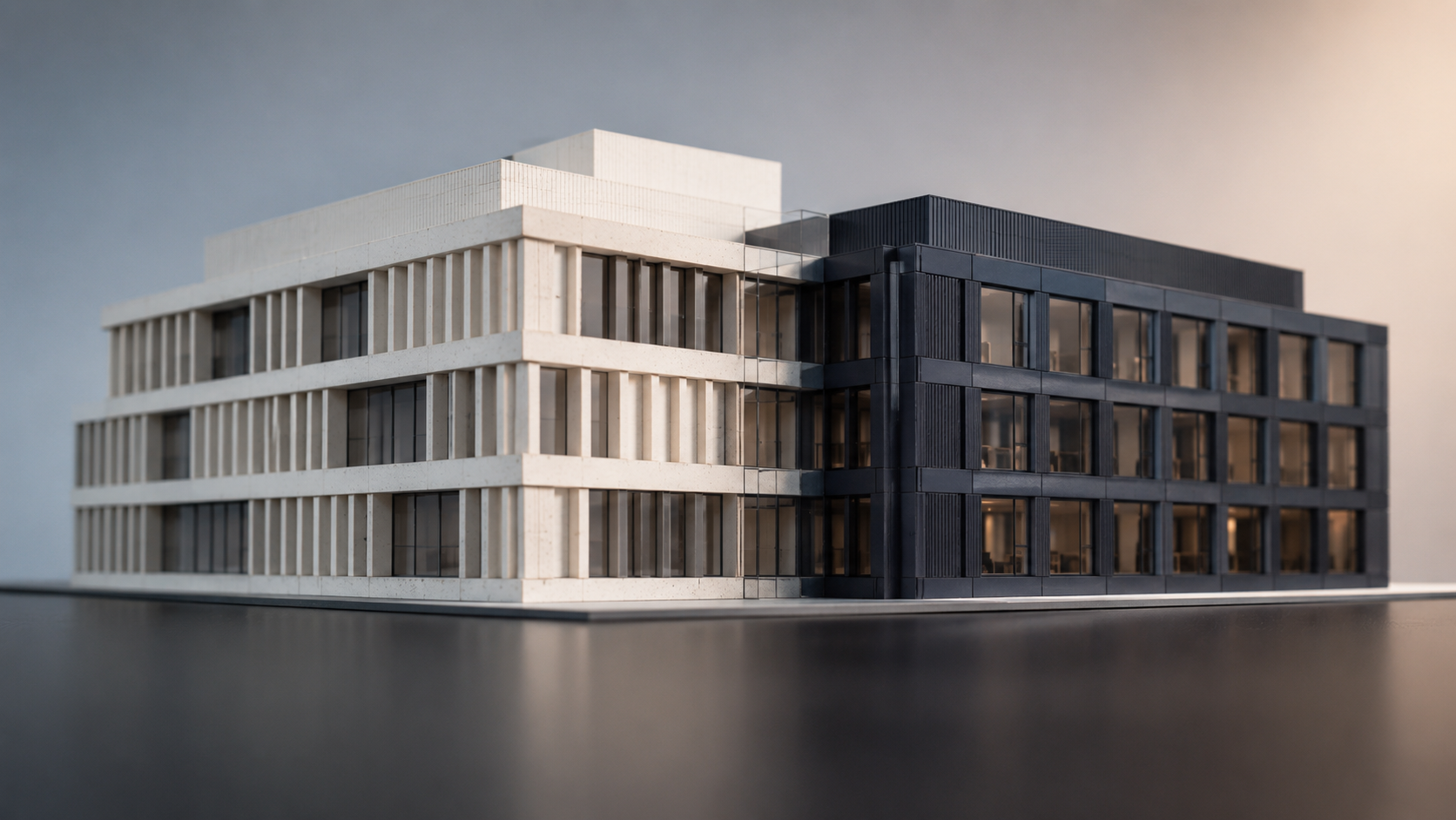 The image shows a detailed architectural model of a modern building featuring a combination of light and dark materials. The structure highlights angular designs with large windows, set against a neutral background.