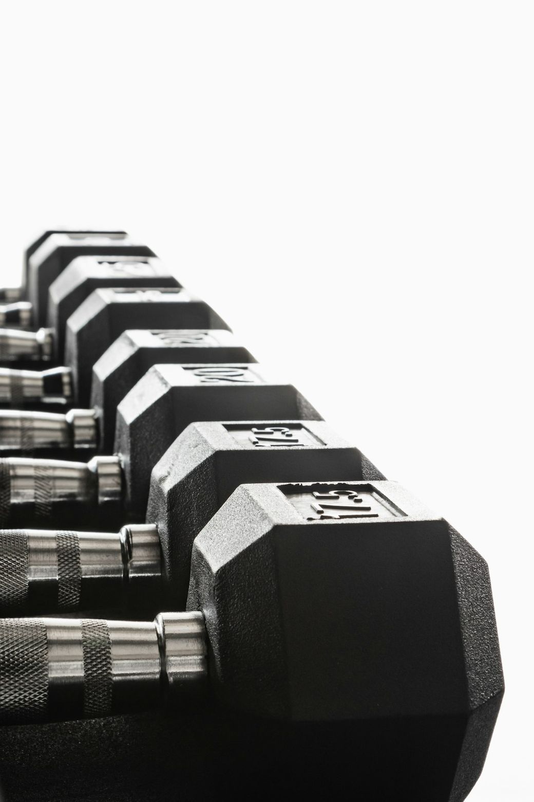 A close-up view of a set of black dumbbells arranged in a row. The dumbbells are made of metal with a textured grip and clearly display their weights. — Credit: Photo by Greg Rosenke on Unsplash