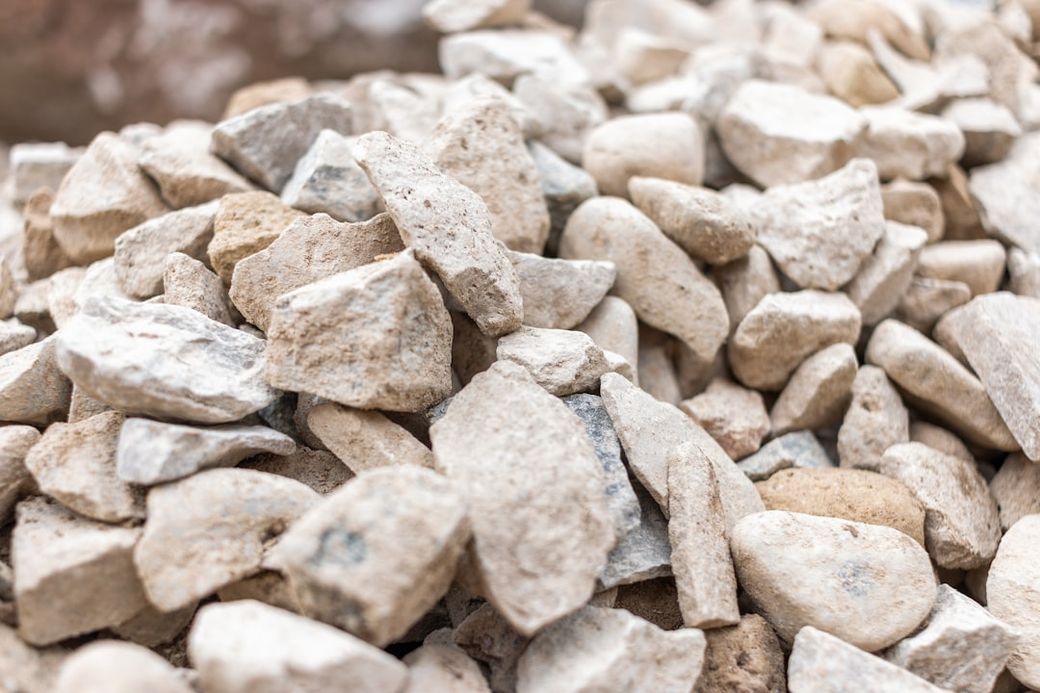 The image shows a close-up of a pile of small, irregularly shaped stones and gravel. The texture and colors of the stones vary, showcasing earth tones and shades of gray. — Credit: Photo by Dylan McLeod on Unsplash