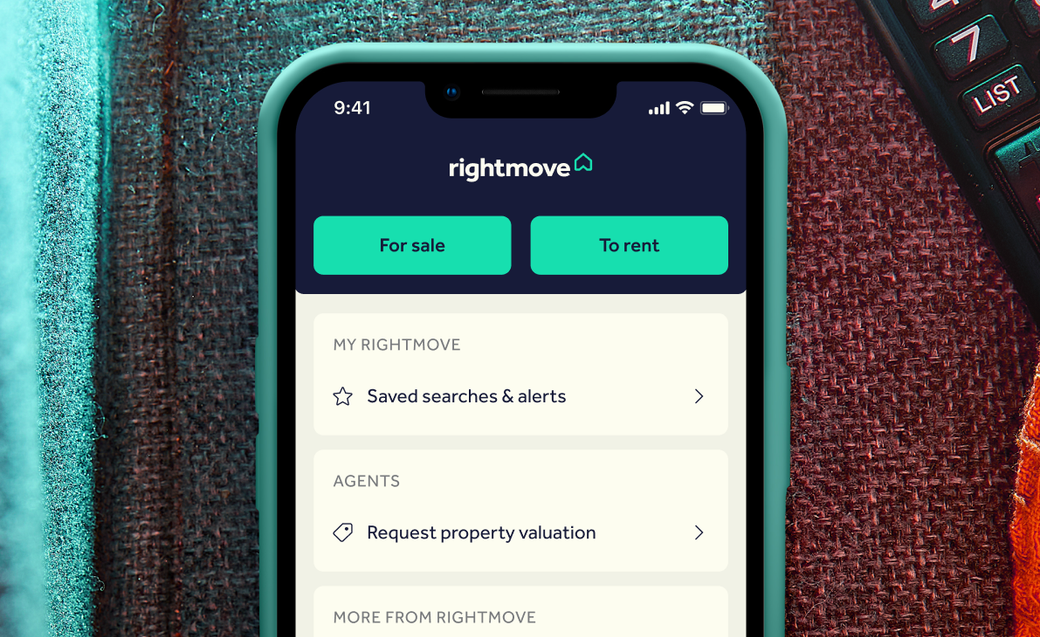 A close-up image of a smartphone displaying the Rightmove app interface. The screen shows options for property listings labeled 'For sale' and 'To rent'. The background includes textures that suggest a home setting.