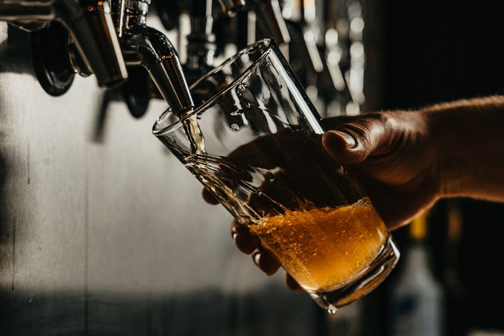 person pouring brown liquid on clear drinking glass — Credit: Photo by Josh Olalde on Unsplash